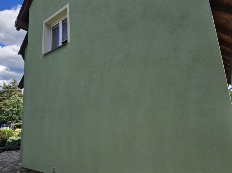 Tatáž fasáda po dokončení čištění metodou Soft Wash — jednolitě čistá zelená barva, jasná obloha