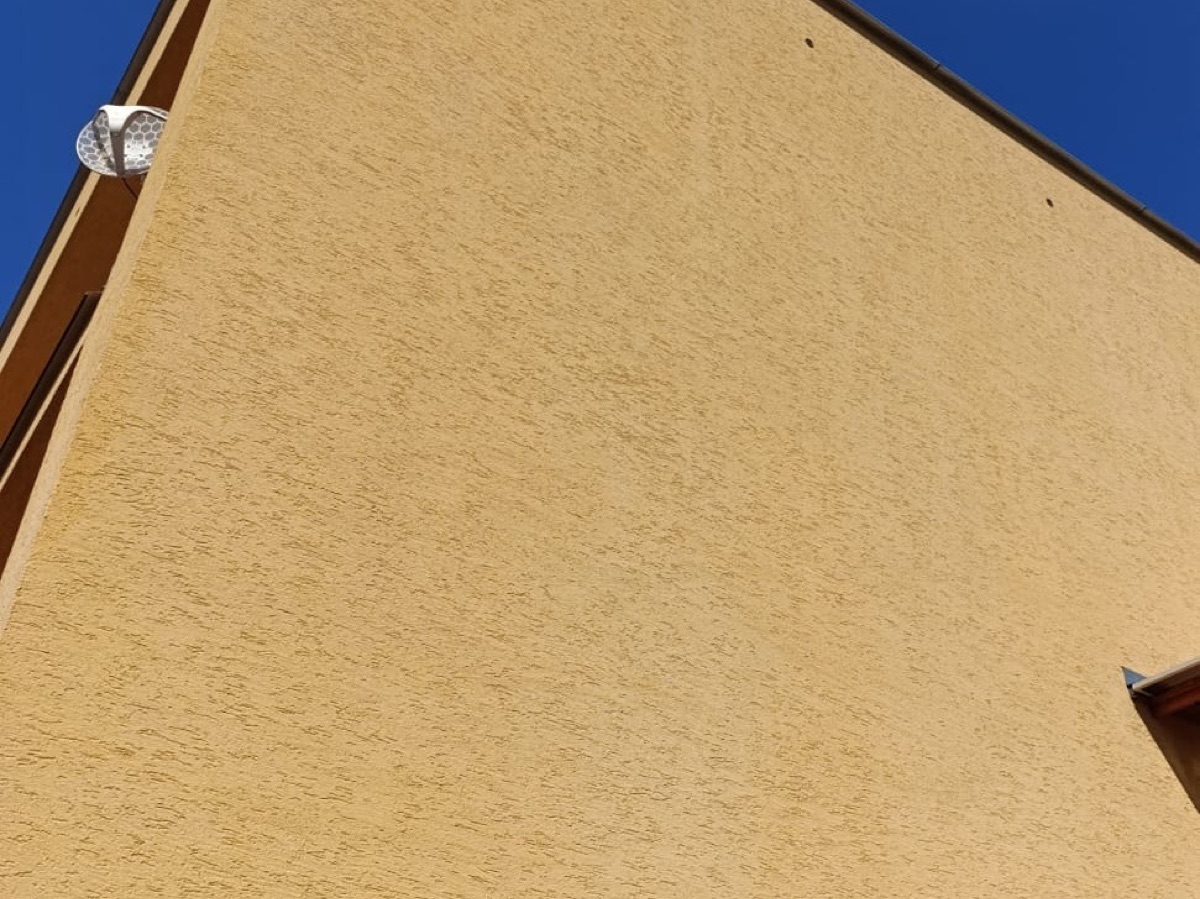 Detailní záběr čisté žluté strukturované omítky s viditelnou jemnou texturou povrchu
