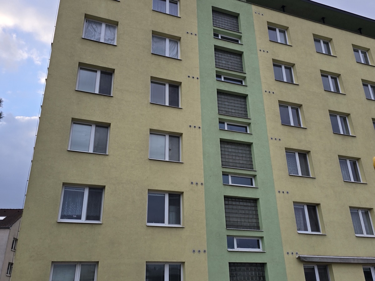 Čistá žlutozelená fasáda panelového bytového domu po dokončeném čištění a impregnaci