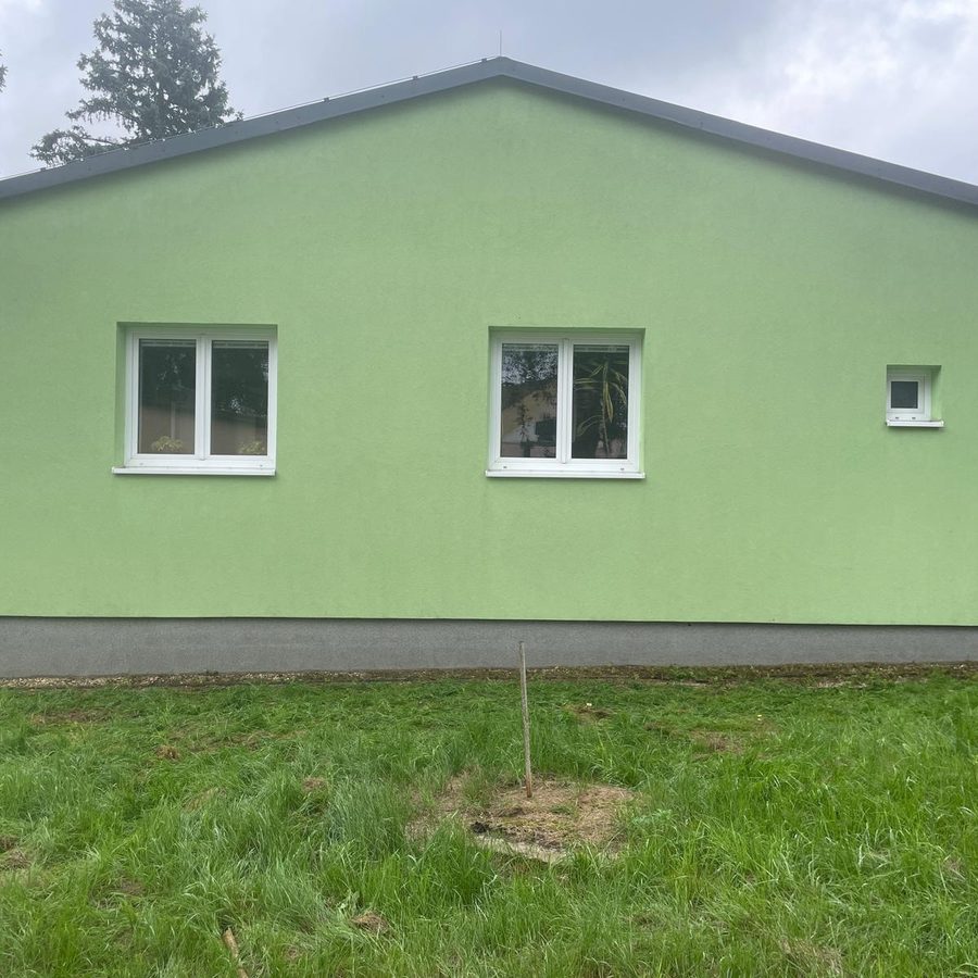 Zelená omítková fasáda přízemního domu se štítem, jednolitá čistá barva bez skvrn