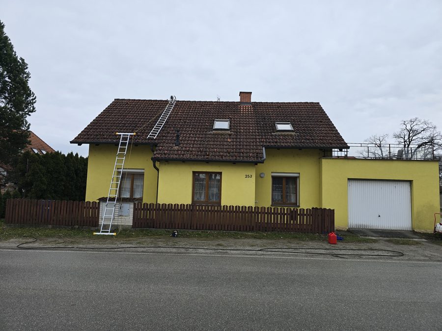 Pálená taška na střeše rodinného domu s tmavým povlakem a černými stružkami, štít i sedlová část