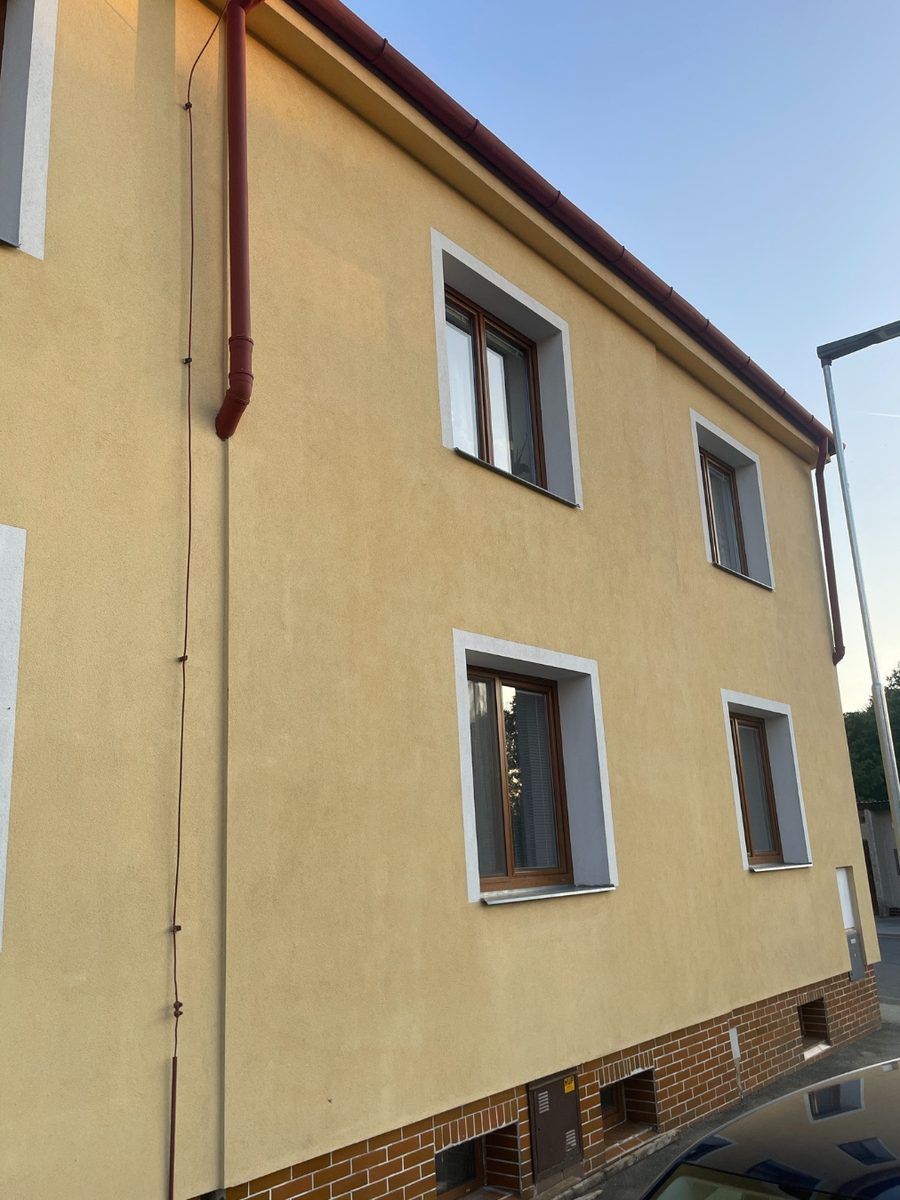 Žlutá omítka rodinného domu bez skvrn, jednotná barva fasády kolem oken