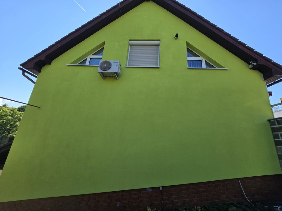 Štít rodinného domu s rovnoměrnou žlutozelenou fasádou po novém nátěru