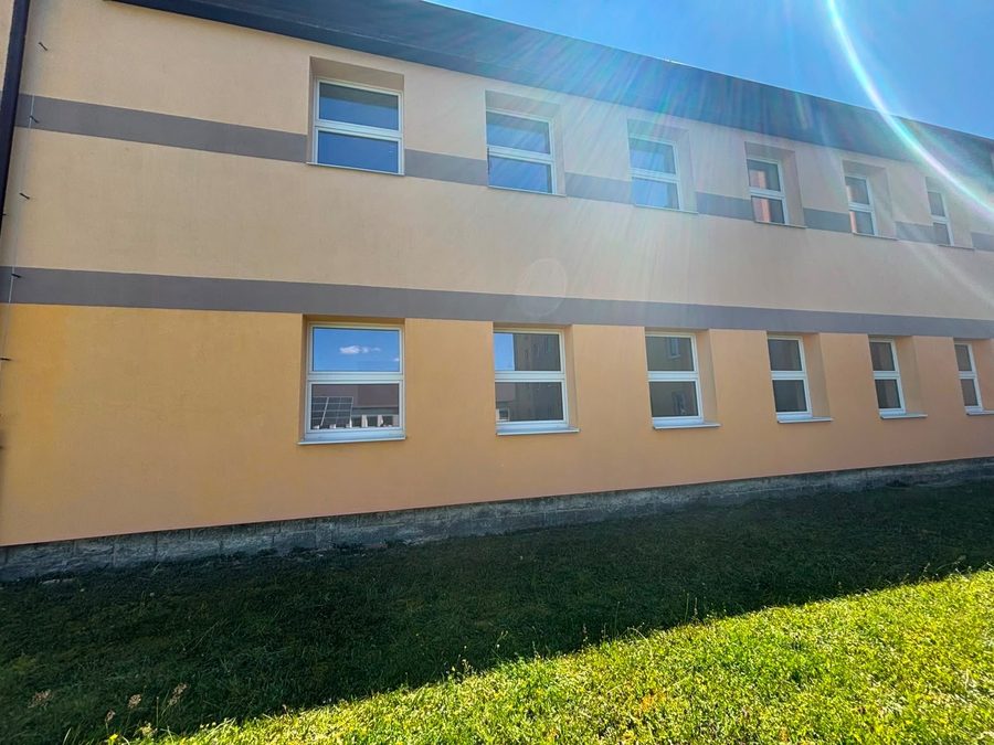 Omítka patrové budovy bez tmavých stružek, jednotná světlá barva fasády