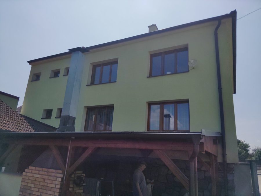 Rohový dům se zelenou omítkou, fasáda bez šedých skvrn, komín a okapy čisté